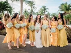 a group of women standing next to each other in yellow dresses and holding bouquets