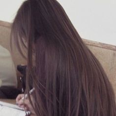 a woman with long brown hair sitting at a desk using a laptop computer