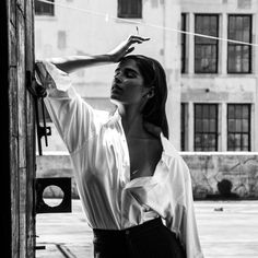 black and white photograph of a woman leaning against a building