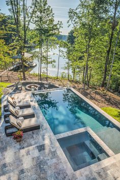 an outdoor swimming pool surrounded by trees and grass with lounge chairs on the patio area