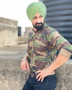 a man wearing a green turban standing next to a wall