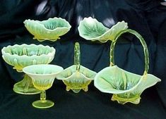 four green glass vases sitting on top of a black cloth