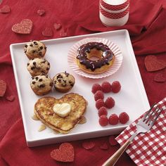 heart shaped pancakes, raspberries and chocolate chip donuts on a white plate