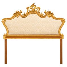 an ornate headboard with gold trimmings and scrolls on the top, against a white background