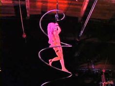 a woman is suspended in the air on a hoop with her hands behind her head