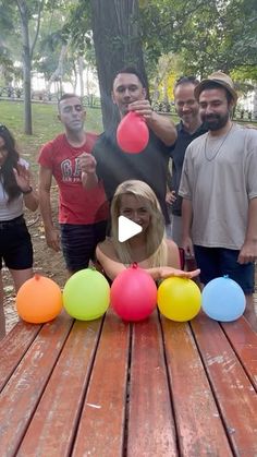 a group of people standing next to each other near a table with balloons on it