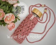 a pink crochet bottle holder next to flowers