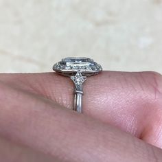 a close up of a person's hand holding a ring with a diamond on it