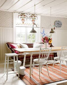 a dining room table with four chairs and a rug on the floor in front of it