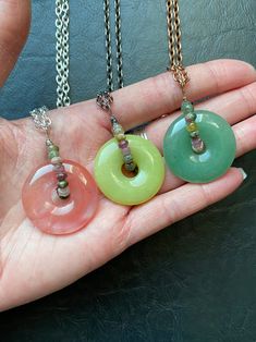 "Another CrackedHaloDesign Original. Gemstone donuts have been lovingly wrapped with high grade faceted rainbow tourmaline beads for a bit of luxurious whimsy. Each circle pendant has its own individual unique beauty created by Mother Nature. These are reversible and may be used as fidget toys or spinners, as each gem moves freely within the wrap. These three are so juicy and exude all the summer vibes! Unique and beautiful to wear everyday. Select your exact pendant and choice of necklace lengt Gemstone Donut Necklace, Crystal Donut Necklace, Donut Crystal Necklace, Tourmaline Jewelry With Round Beads As Gift, Spiritual Jade Crystal Necklaces With Round Shape, Wire Wrapped Round Agate Jewelry, Handmade Tourmaline Dangle Jewelry, Handmade Round Spiritual Gemstones, Pink Jade Jewelry With Natural Stones