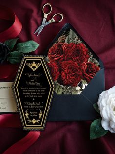 a bouquet of red roses sits next to an envelope with a wedding card on it