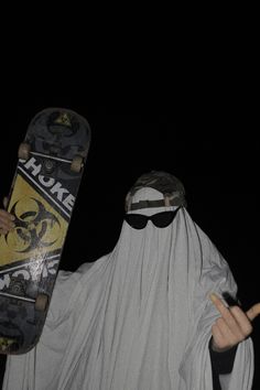 a man dressed as a nun holding a skateboard in one hand and making the peace sign