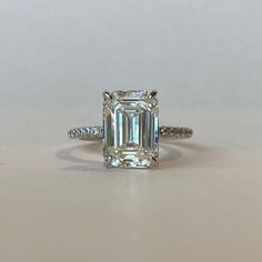 an emerald cut diamond ring with diamonds around it