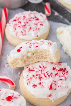 cookies with white frosting and candy canes are on a baking sheet, ready to be eaten