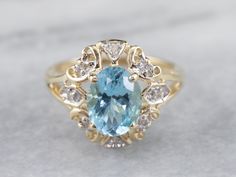 A perfect sky blue hue radiates from the center of this classic piece. This oval-cut blue topaz has been set in a scrolling filigree halo of glittering diamonds and a frame of yellow gold, this vintage ring has plenty of light and life, and will wear beautifully day or night.Metal: 10K Yellow Gold Gem: Blue Topaz 2.30 Carats Gem Measurements: 8.9 x 6.8 mm, OvalAccents: 8 Diamonds totaling .08 Carats, I in Color, SI2 in Clarity Ring Size: 7Marks: "10K A @" Stamped on the inside band Diamond Halo Ring, Diamond Glitter, Watch Chain, Halo Diamond Ring, Halo Ring, Halo Rings, Diamond Halo, Vintage Ring, Pearl Pendant