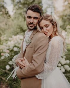 a bride and groom embracing each other in front of white flowers at their wedding day