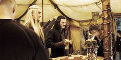 a group of people standing around a table with food on it and candles in front of them