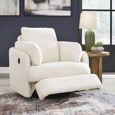 a white reclining chair sitting on top of a rug next to a table with a lamp