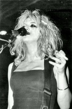 a woman with blonde hair singing into a microphone