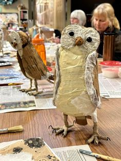 an owl made out of toilet paper sitting on top of a table next to other papers