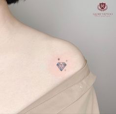 a woman's chest with a diamond tattoo on the left side of her breast