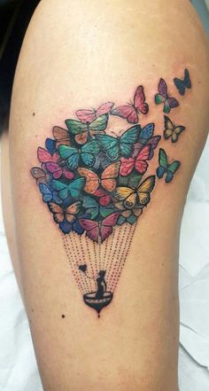 a woman's thigh with colorful butterflies flying in the sky and holding onto a kite