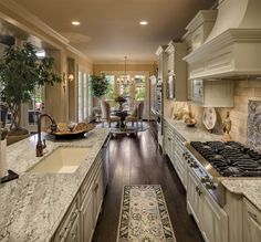 a large kitchen with white cabinets and marble counter tops