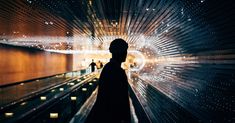 the silhouette of a man standing in an escalator with lights shining down on him