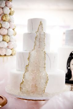 a white and gold wedding cake sitting on top of a table next to other decorations