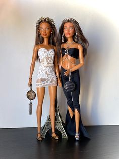 two dolls standing next to each other in front of the eiffel tower,