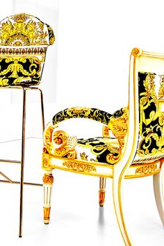 an elaborately decorated chair sits next to a bar stool that is gold and black