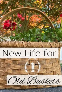 a basket filled with flowers sitting on top of a wooden table next to a sign that says new life for old baskets