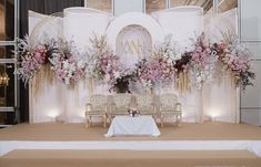 a table with chairs and flowers on it in front of a stage set up for a wedding