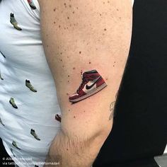 a person with a tattoo on their arm has a pair of sneakers in the shape of a shoe