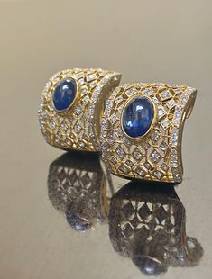 DeKara Designs Collection Metal- 18K White Gold, .750. 15.50 Grams. Stones- 2 Genuine Cabochon Oval Ceylon Blue Sapphires 5.02 Carats, 168 Round Diamonds F-G Color SI2 Clarity 2 Carats. One of a kind entirely handmade, Art Deco 18K Yellow Gold Sri Lanka Ceylon Cabochon Cut Blue Sapphire and Pave Set Diamond Art Deco Inspired One of a Kind Earrings. Each earring has an amazing oval cabochon blue sapphire that is professionally and uniquely bezel/burnish set. There are 79 round pave set diamonds o Luxury Cabochon Clip-on Earrings For Formal Occasions, Oval Sapphire Earrings With 17 Jewels, Luxury Oval Earrings For Formal Occasions, Luxury Oval Clip-on Earrings For Anniversary, Blue Fine Jewelry Earrings For Formal Occasions, Luxury Oval Yellow Gold Earrings, Luxury Yellow Gold Oval Earrings, Exquisite Cabochon Earrings For Formal Occasions, Exquisite Formal Cabochon Earrings