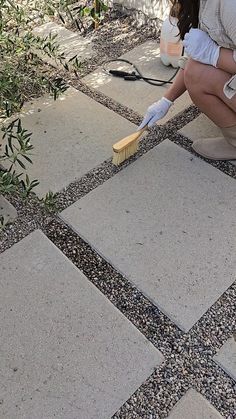 a woman kneeling down on the ground with a brush in her hand and scrubbing it