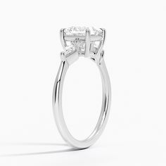 Princess Cut Cometa Three Stone Diamond Engagement Ring - 18K White Gold. Elegant and chic, this three stone ring features two kite-shaped diamond accents alongside a center gemstone cradled by lustrous claw prongs. The sleek, sophisticated band gently tapers down into a low dome for increased comfort (1/10 total carat weight). Three Stone Diamond Rings Engagement, Three Stone Diamond Ring, Three Stone Diamond, Three Stone Ring, Engagement Rings Platinum, White Gold Diamond Rings, Hidden Halo, Halo Diamond Ring, Halo Diamond Engagement Ring