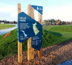 a blue sign sitting on the side of a lush green field next to a park