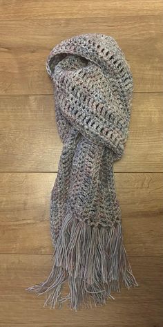 a knitted scarf with fringes on top of a wooden floor