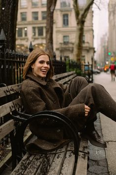 a woman sitting on top of a wooden bench