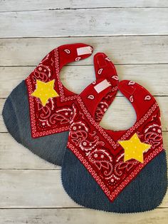 two red bandanna bibs with yellow stars on them sitting on a wooden surface