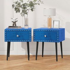 two blue nightstands with black legs and studded accents on each side, against a white wall