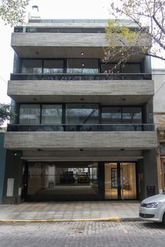 a car parked in front of a tall building with balconies on the second floor