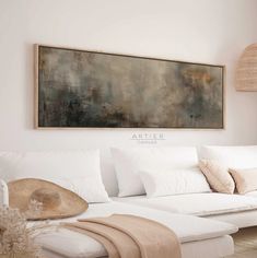 a living room with a large painting on the wall and white couches in front of it