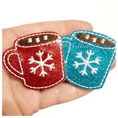 two handmade christmas mugs with snowflakes on them, one red and one blue