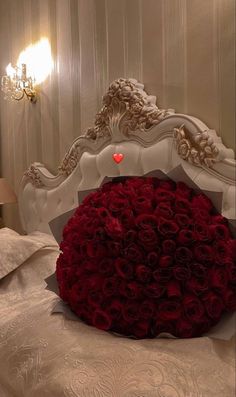 a large bouquet of red roses sitting on top of a white bed in a bedroom