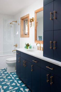 a blue and white bathroom with gold handles on the vanity, toilet and shower stall