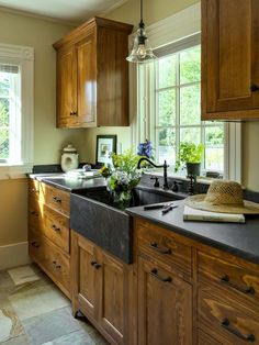 a kitchen with wooden cabinets and black counter tops, along with a large window above the sink