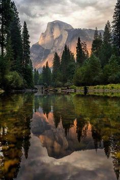 the mountains are reflected in the still water of this mountain lake, with trees and rocks surrounding it