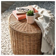 a wicker table topped with a potted plant next to eyeglasses and books